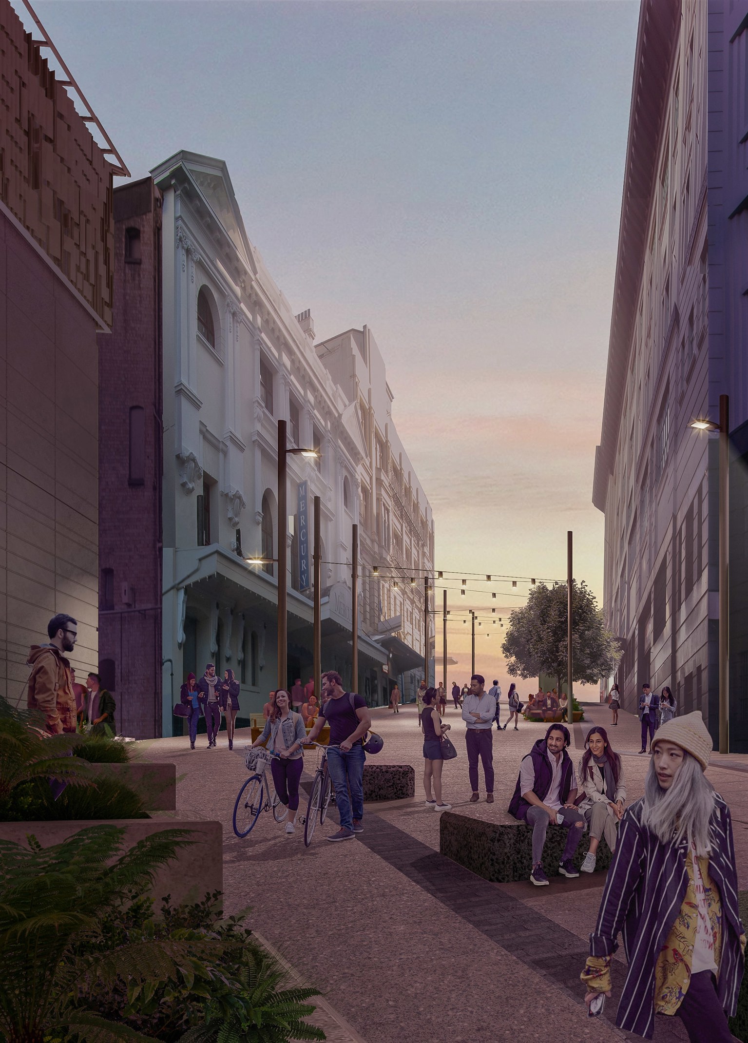 People walking their bikes and hanging out in a paved pedestrian area between buildings at sunset. Overhead string lights, planters and seating areas accent the space. 